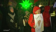 Bei einer Demonstration gegen die AfD und Rechtsextremismus in Stralsund: Demonstrantinnen und Demonstranten mit Plakaten, eine Frau im Vordegrund trägt ein Plakat mit der Aufschrift: "Braune Birnen aussortieren". © Screenshot 