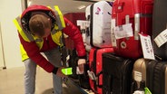 Ein Mitarbeiter der Gepäckservice-Firma Tefra scannt die Etiketten von Koffern. © Screenshot 
