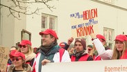 Ärztinnen und Ärzte streiken vor einem Uni-Klinikum. © Screenshot 