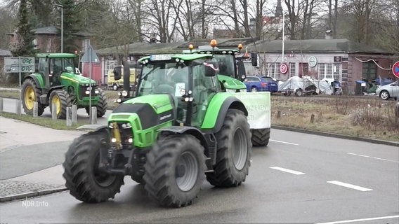 Eine Reihe Traktoren fährt eine Straße entlang. © Screenshot 