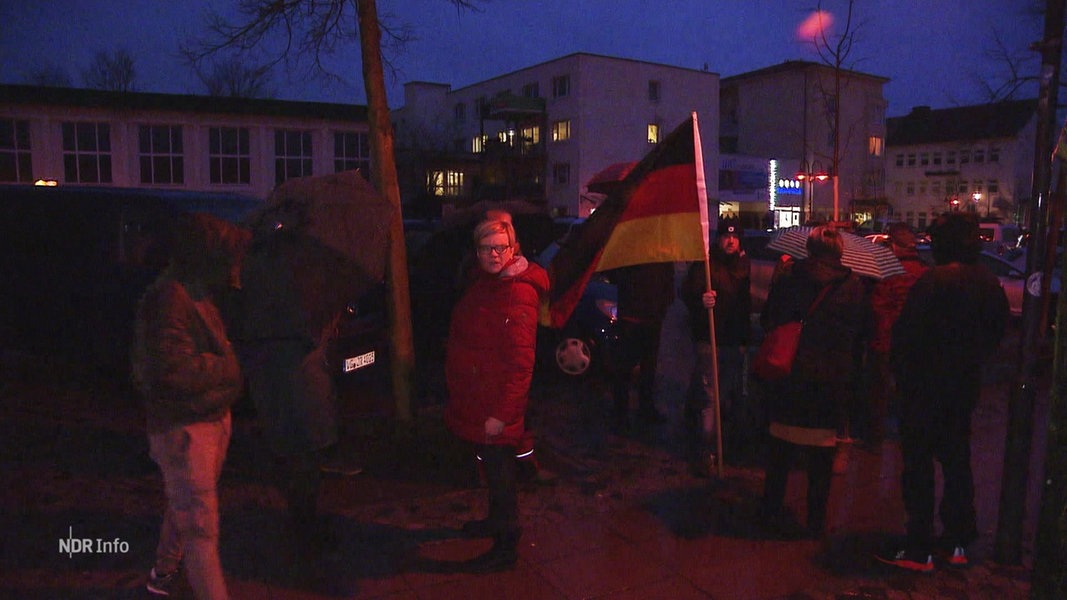Eine kleine Gruppe Menschen steht mit einer Deutschland Flagge auf der Straße.
