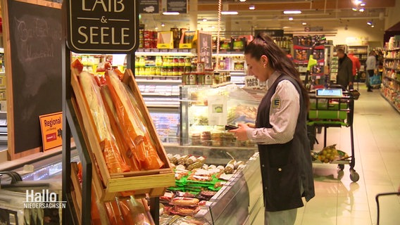 Eine Mitarbeiterin steht an einer Kühltheke in einem Supermarkt. © Screenshot 