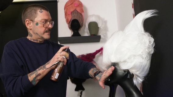 Friseurmeister Karl Gadzali besprüht eine Perücke mit Spray. © Screenshot 