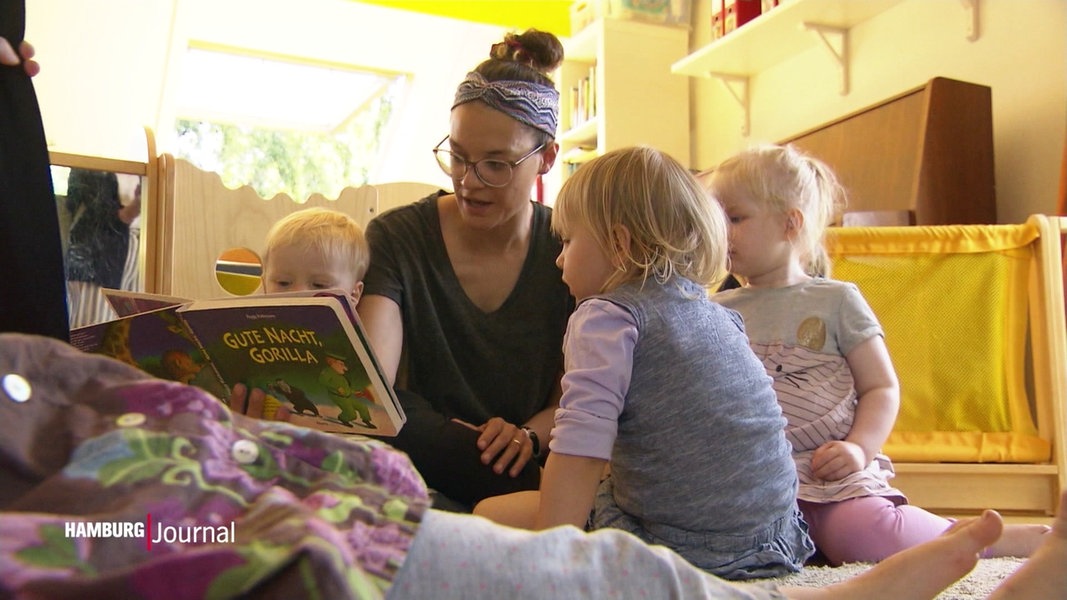 Eine Frau schaut mit drei Kleinkindern ein Buch an.