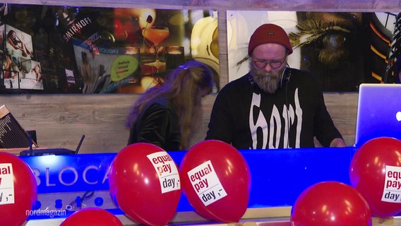 Ein DJ-Pult, geschmückt mit roten Luftballons mit dem Aufdruck: Equal Pay Day. © Screenshot 