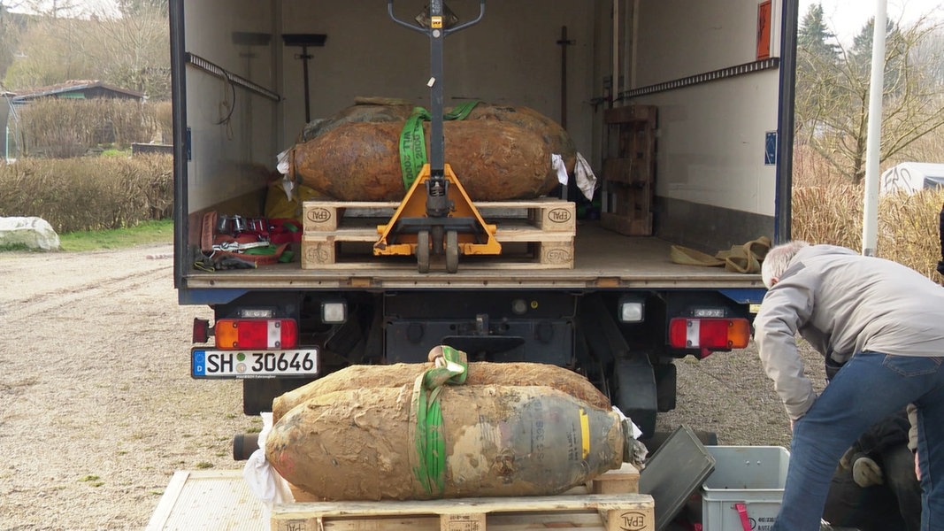 Vier entschräfte amerikanische Fliegerbomben werden in einen Lastwagen verladen.