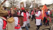 Medizinerinnen und Mediziner streiken in pinken Warnwesten. © Screenshot 