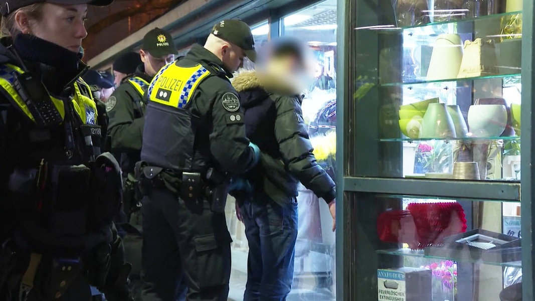 Ein Polizist kontrolliert eine Person am Hamburger Hauptbahnhof.