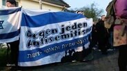 Eine Gruppe mit einem Banner auf dem "Gegen jeden Antisemitismus" steht. © Screenshot 