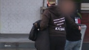 Zwei Personen laufen nebeneinander. Auf dem Rücken der einen, steht auf dem Pullover: Kalifat. © Screenshot 