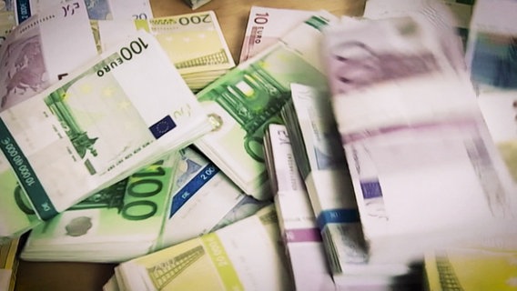 Mehrere Bündel mit Euro-Geldscheinen. © Screenshot 