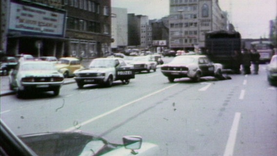 Alte Videoaufnahmen von 1974. Polizeiauto stehen ungeordnet auf einer Straße am Steindamm, einige Autotüren sind geöffnet. © Screenshot 