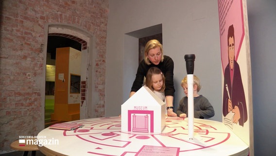 Zwei Kinder und eine Frau beschäftigen sich mit der interaktiven Ausstellung des Hansemuseums in Lübeck zum Thema "Navigation". © Screenshot 