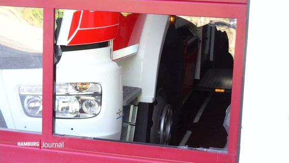 Blick durch eine eingeschlagene Scheibe eines Rolltores auf ein dahinter parkendes Fahrzeug der Feuerwehr. © Screenshot 