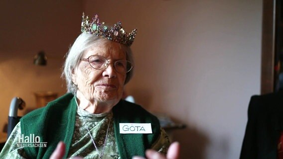Eine Seniorin mit Namensschild "Göta" trägt eine Krone © Screenshot 