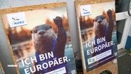 Plakate vom NABU zur Europawahl: Auf den Postern ist die Figur eines Otters zu sehen, der die Pfote hebt, darunter der Spruch: "Ich bin Europäer". © Screenshot 