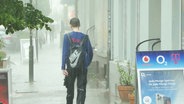 Eine komplett durchnässte Person, die durch strömenden Regen läuft, von hinten gesehen. © Screenshot 