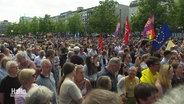 Blick auf eine Menge von Menschen. Einige halten Flaggen, darunter die EU-Flagge hoch. © Screenshot 