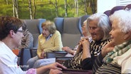 Mehrere Seniorinnen sitzen in Sesseln und unterhalten sich miteinander. © Screenshot 