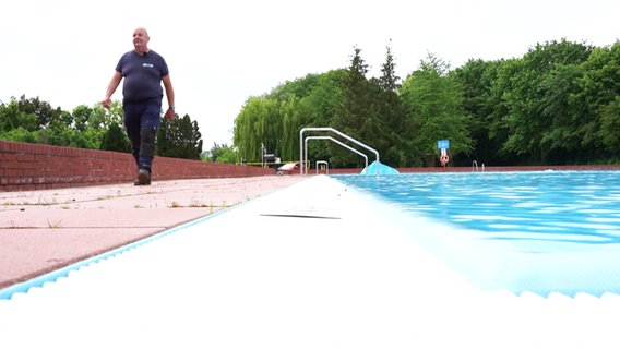 Ein Person am Rande eines Schwimmbeckens in einem Freibad. © Screenshot 
