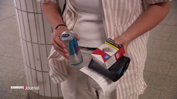 Eine Person hält eine Dose und eine Zigarettenschachtel in den Händen. © Screenshot 