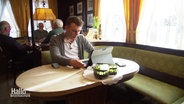 Der Start-up-Gründer Martin Meyer sitzt mit seinem Laptop an einem Tisch in einer Kneipe. © Screenshot 