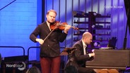 Zwei Männer geben ein klassisches Konzert. Der eine spielt Violine, der andere sitzt am Flügel. © Screenshot 