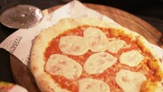 Eine ofenfrische Pizza ist mit einer veganen Mozzarella-Alternative belegt. © Screenshot 