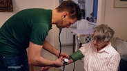 Sören Runge misst während eines hausbesuchs den Blutdruck einer alten Frau. © Screenshot 