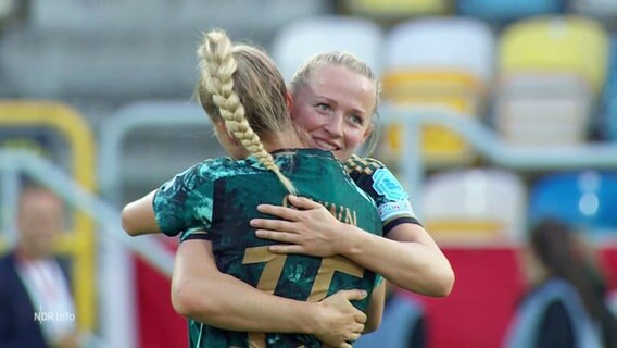 Nationalspielerinnen Gwinn und Schüller umarmen sich auf dem Platz. © Screenshot 