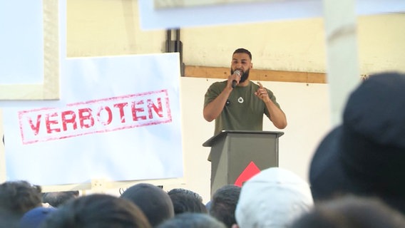 Ein Redner von Muslim Interaktiv steht bei einer Demonstration auf der Bühne. © Screenshot 