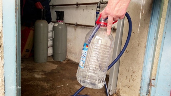 Menschen müssen Wasser aus einer Aufbereitungsanlage holen, da ihr Leitungswasser mit Arsen vergiftet ist. © Screenshot 