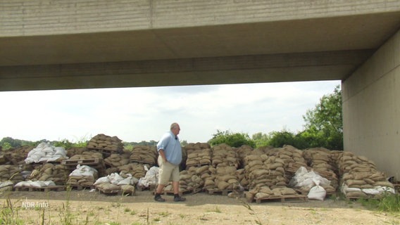 Ein großer Haufen Sandsäcke unter einer Brücke, davor begutachtend der Ruther Bürgermeister. © Screenshot 