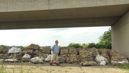 Ein großer Haufen Sandsäcke unter einer Brücke, davor begutachtend der Ruther Bürgermeister. © Screenshot 