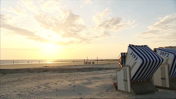 An einem norddeutschem Strand stehen Strandkörbe bei tiefstehender Sonne. © Screenshot 
