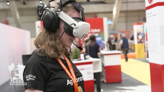 Ein Mädchen trägt eine Virtual-Reality-Brille auf einer Messe. © Screenshot 