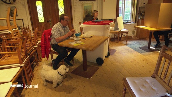 Zwei Wahlhelfer und ein Hund in einem Wahllokal © Screenshot 
