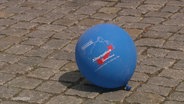 Ein AfD-Luftballon liegt auf einer Straße. © Screenshot 