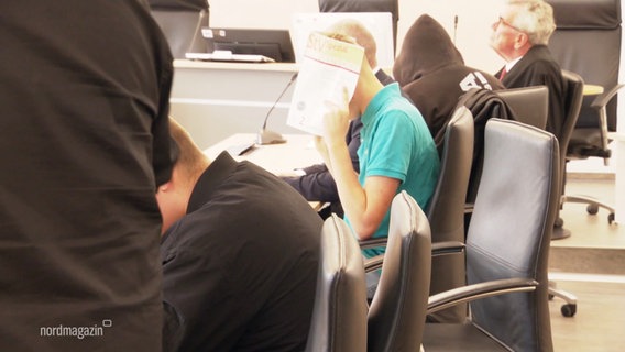 Ein Jugendlicher hält sich im Gerichtssaal eine Mappe vor sein Gesicht. © Screenshot 