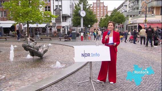 Romy Hiller moderiert draußen auf einem Marktplatz in Rostock. © Screenshot 