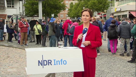 Romy Hiller moderiert draußen auf einem Marktplatz in Rostock. © Screenshot 