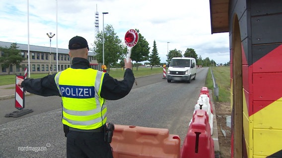 Ein Polizist mit Warnweste und Kelle winkt Autos bei einer Grenzkontrolle an die Seite. © Screenshot 