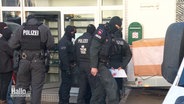 Polizei-Einsatzkräfte in schwarzer Uniform während der Razzia. © Screenshot 