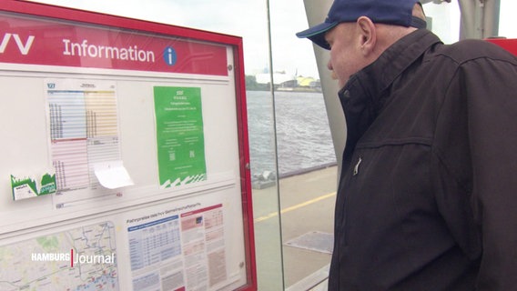 Ein Mann betrachtet skeptisch einen Aushang am HVV Fahrplan. © Screenshot 