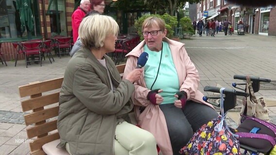 Susanne Stichler sitzt auf eineer Bank und interviewt eine Dame, die neben ihr sitzt. © Screenshot 