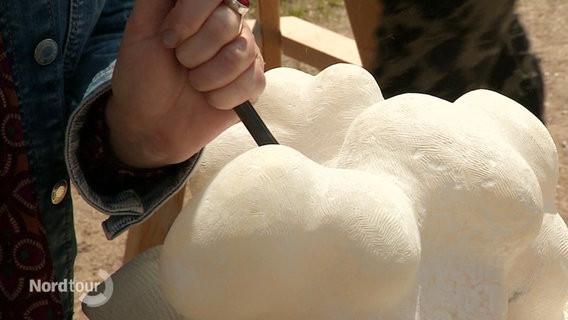 Weißer Stein wird kunstvoll mit Hammer und Meißel bearbeitet. © Screenshot 