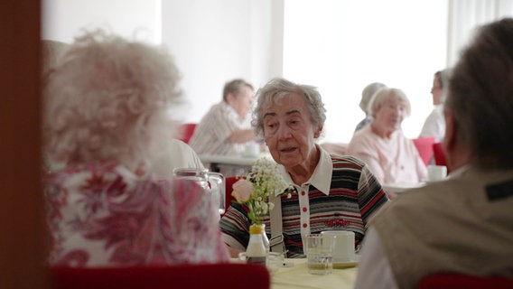 Senioren sitzen gemeinsam an gedeckten Tischen zu Kaffee und Kuchen. © Screenshot 
