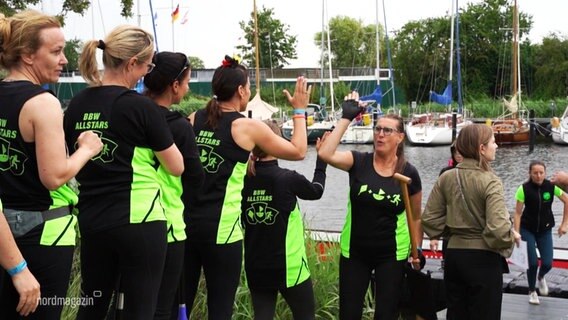 Ein teilnehmendes Team steht am Ufer und klatscht sich ab. © Screenshot 