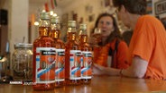 Mehrere Flaschen Oranje-Schnaps stehen auf einem Tresen © Screenshot 