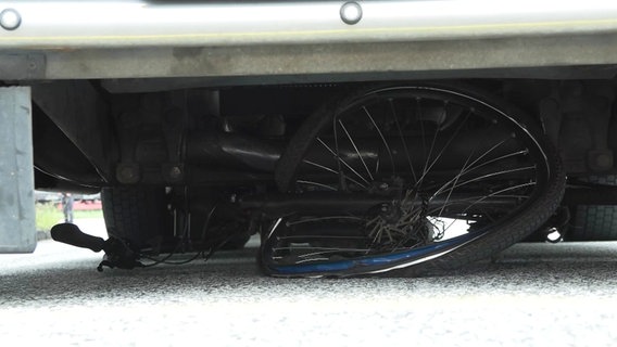 Ein verbeultes Fahrrad klemmt unter einem LKW. © Screenshot 